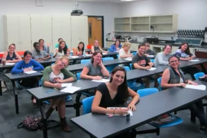 A group of university students in the ANS 3251 course sitting at laboratory desks, smiling and looking toward the camera during an academic session in a classroom.