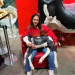 Outreach Rachel in a red sweater sits in a red chair holding a life-sized calf model at the Royal Winter Fair 2025.
