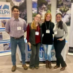 Outreach Four university researchers pose together in front of a "Dairy at Guelph" display and institutional banners during the Dairy at Guelph Research Showcase 2024.