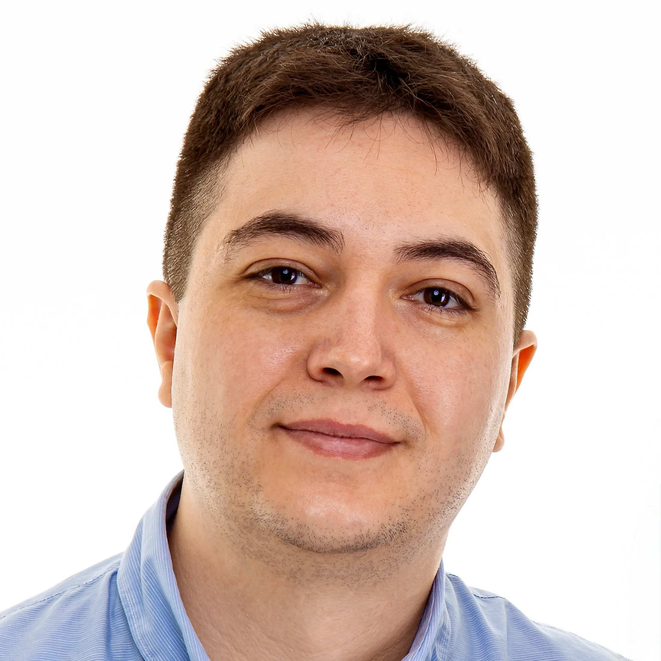 Members Professional headshot of a man with short brown hair and a light blue button-down shirt, smiling slightly against a white background.